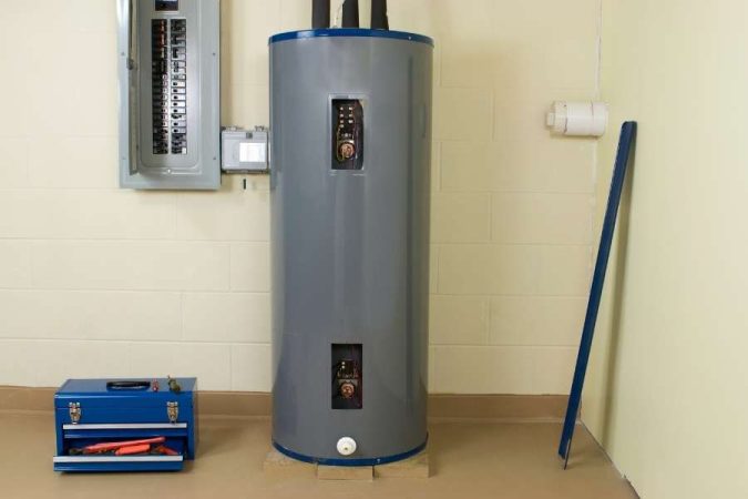 Un grand chauffe-eau cylindrique gris installé dans une pièce technique, pouvant être à l'origine d'une odeur d'œufs pourris en cas de problème de thermostat ou d'anode.