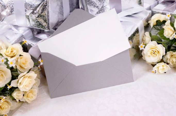 Enveloppe grise élégante ouverte avec carte blanche vierge pour illustrer comment formuler un mariage sans enfants invitation.